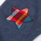 Close up of the festive check stars on the knees of the Frugi organic cotton ronnie reversible pull up trousers.