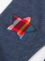 Close up of the festive check stars on the knees of the Frugi organic cotton ronnie reversible pull up trousers.