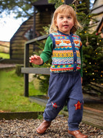 Child wearing the Frugi organic cotton ronnie reversible pull up trousers on the navy cord with festive check star knee patches side with a fairisle style knitted waistcoat and green long sleeved top underneath.
