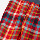 Close up of the Frugi organic cotton ronnie reversible pull up trousers on the festive check side with a navy elasticated waist band.