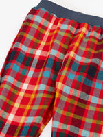 Close up of the Frugi organic cotton ronnie reversible pull up trousers on the festive check side with a navy elasticated waist band.