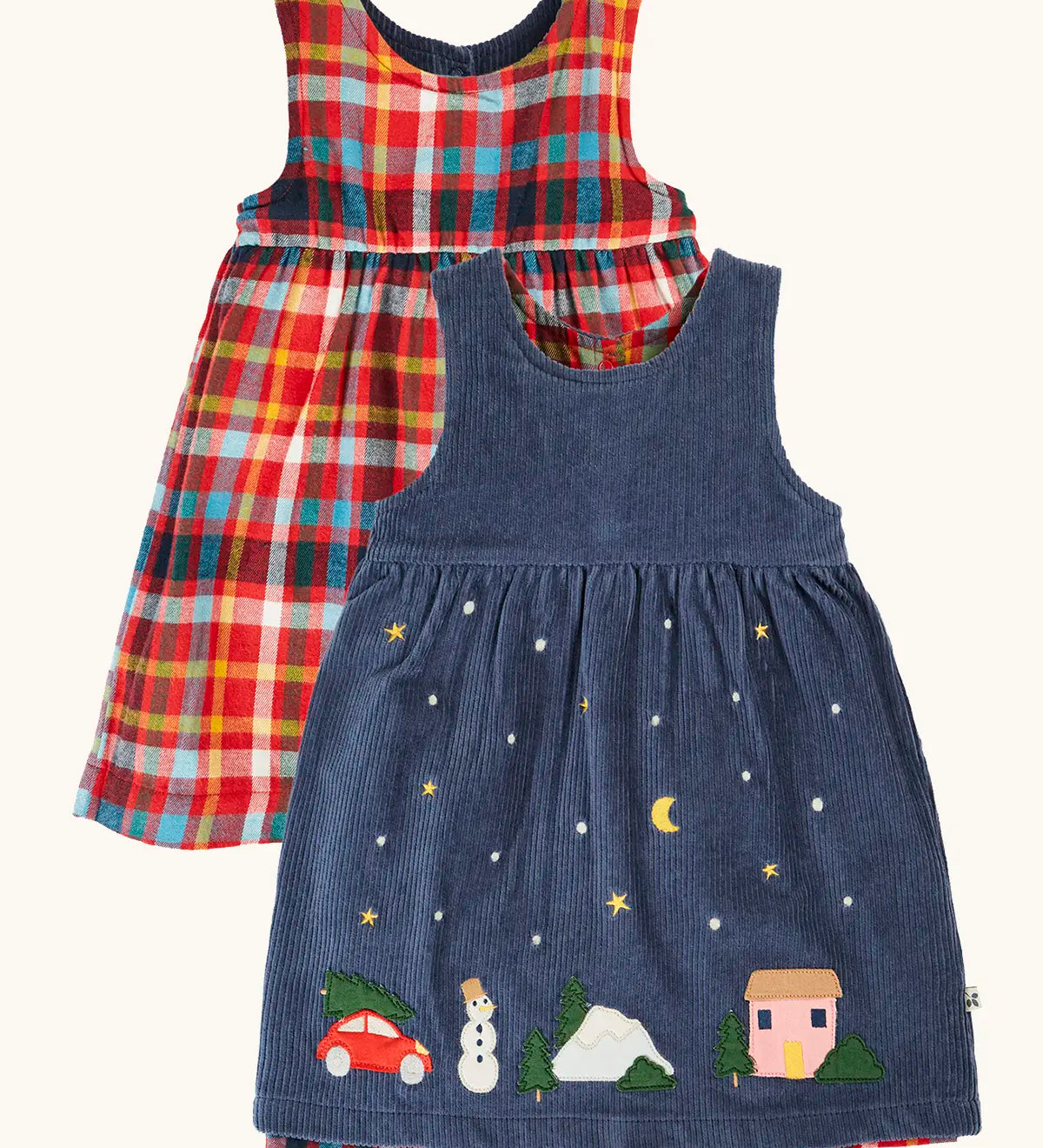 Frugi organic cotton rosalie reversible dress, one side in navy corduroy with appliques on the hemline and snow and stars on the skirt. One side in festive multicoloured check