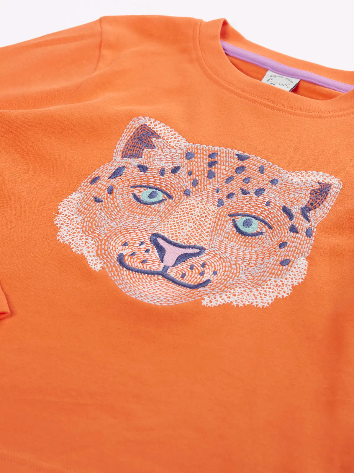 Close up of the Frugi snow leopard organic cotton salamander orange long sleeve top.