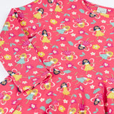 Close up of the Frugi GOTS organic cotton long sleeved sofia skater dress in fairy flutter. Pink background with colourful fairy print featuring flowers and leaves.