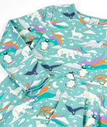 Close up of the Frugi GOTS organic cotton long sleeved sofia skater dress in polar aurora. Blue background with and all over print featuring artic animals among star and colourful swishes. 