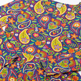 Close up of the details on the Frugi GOTS organic cotton sofia skater dress in pretty paisley. Purple background with colourful paisley print featuring floral and rainbow details.