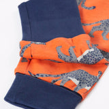 Close up of the navy extendable leg cuffs on the trousers from the Frugi organic cotton sundown kids long sleeve pyjama set with a leopard leap print. 