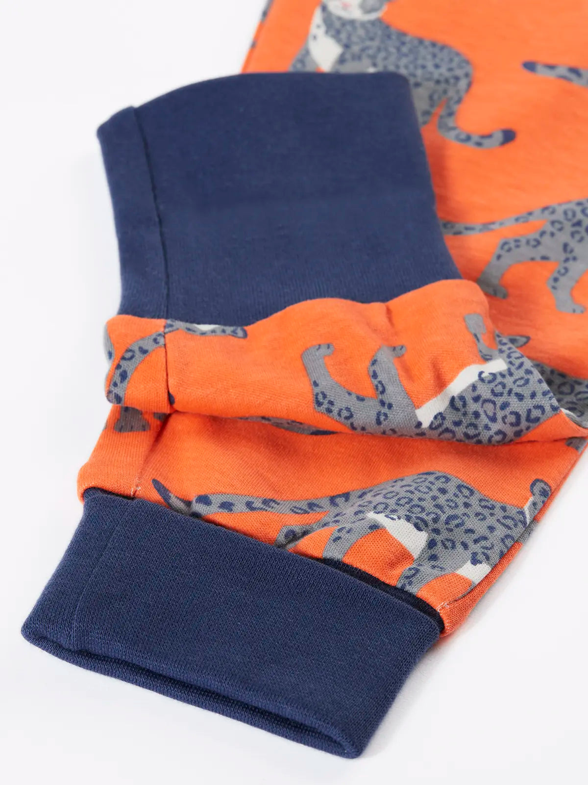 Close up of the navy extendable leg cuffs on the trousers from the Frugi organic cotton sundown kids long sleeve pyjama set with a leopard leap print. 