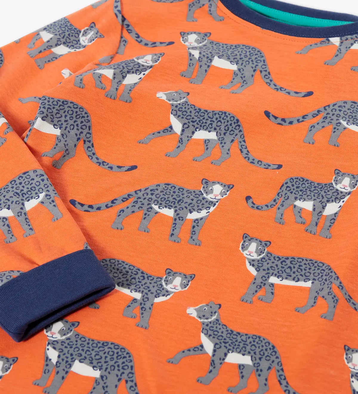 Frugi organic cotton sundown kids long sleeve pyjama set with a leopard leap print. Orange long sleeved pyjama top and matching trousers featuring an all over repeat print of grey leopards with navy cuffs and neck trim.