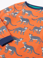 Frugi organic cotton sundown kids long sleeve pyjama set with a leopard leap print. Orange long sleeved pyjama top and matching trousers featuring an all over repeat print of grey leopards with navy cuffs and neck trim.