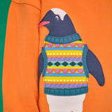 Close up of the penguin applique on the Frugi organic cotton superb sweatshirt salamander orange.