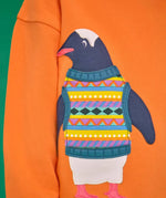 Close up of the penguin applique on the Frugi organic cotton superb sweatshirt salamander orange.