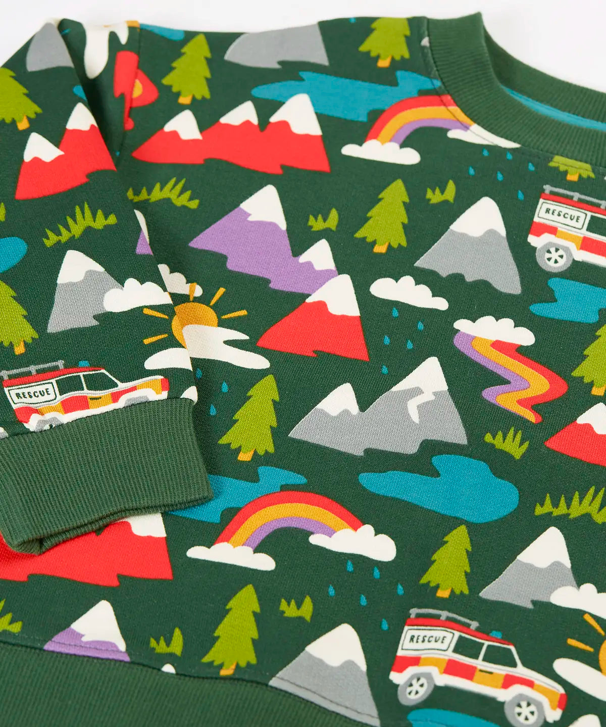 Close up of the rescue trails print on the Frugi organic cotton superb sweatshirt. Bottle green background with colourful snow topped mountains, trees, water, rainbows and a rescue vehicle jeep.