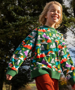 Child wearing the Frugi GOTS organic cotton superb sweatshirt with rescue trails print with rust orange corduroy trousers.