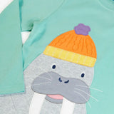Close up of the Frugi organic cotton adventure circular long sleeved top in light moss green with a walrus wearing a bobble hat applique on the front. 