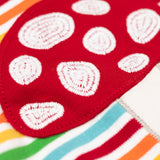 A super close up of the red mushroom applique on the front of the Frugi orion long sleeved, rainbow coloured breton striped child's organic cotton top.