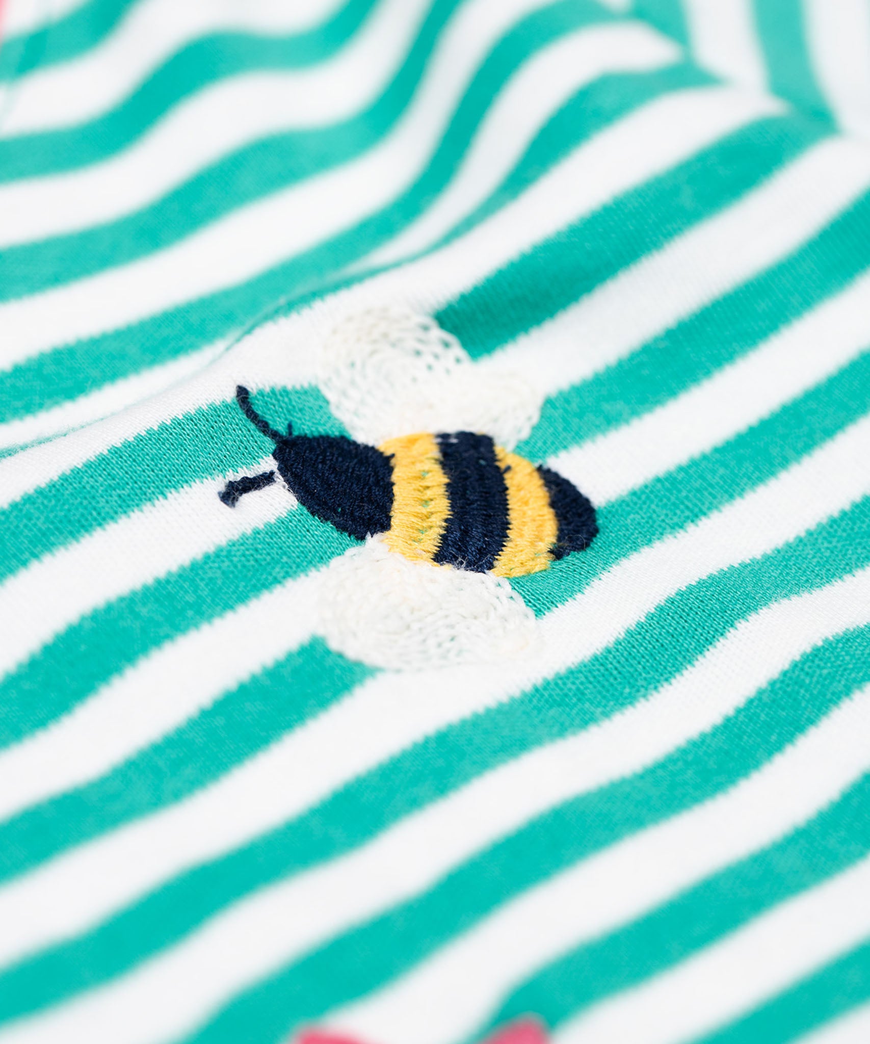 A close up of the embroidered bee detail on the front of the Frugi Orion flowers long sleeved kids top. 