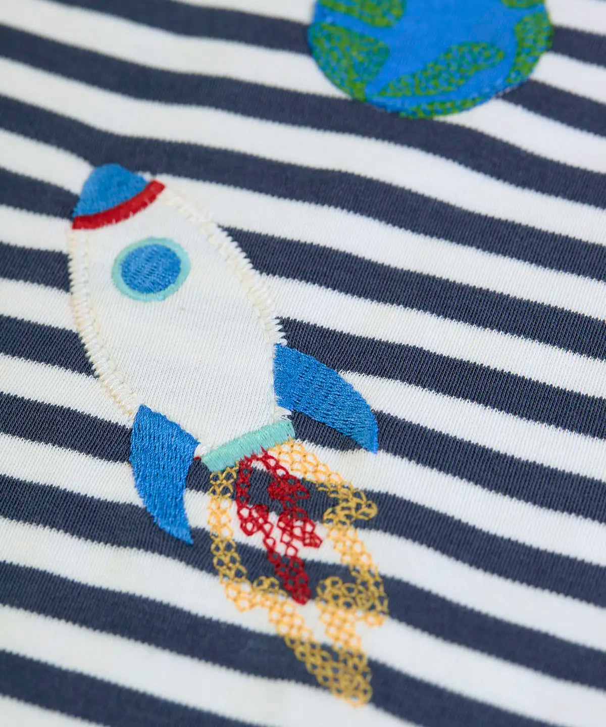 Frugi GOTS 100% organic cotton kids long sleeve top in navy and white stripes showing a close up of a rocket applique 