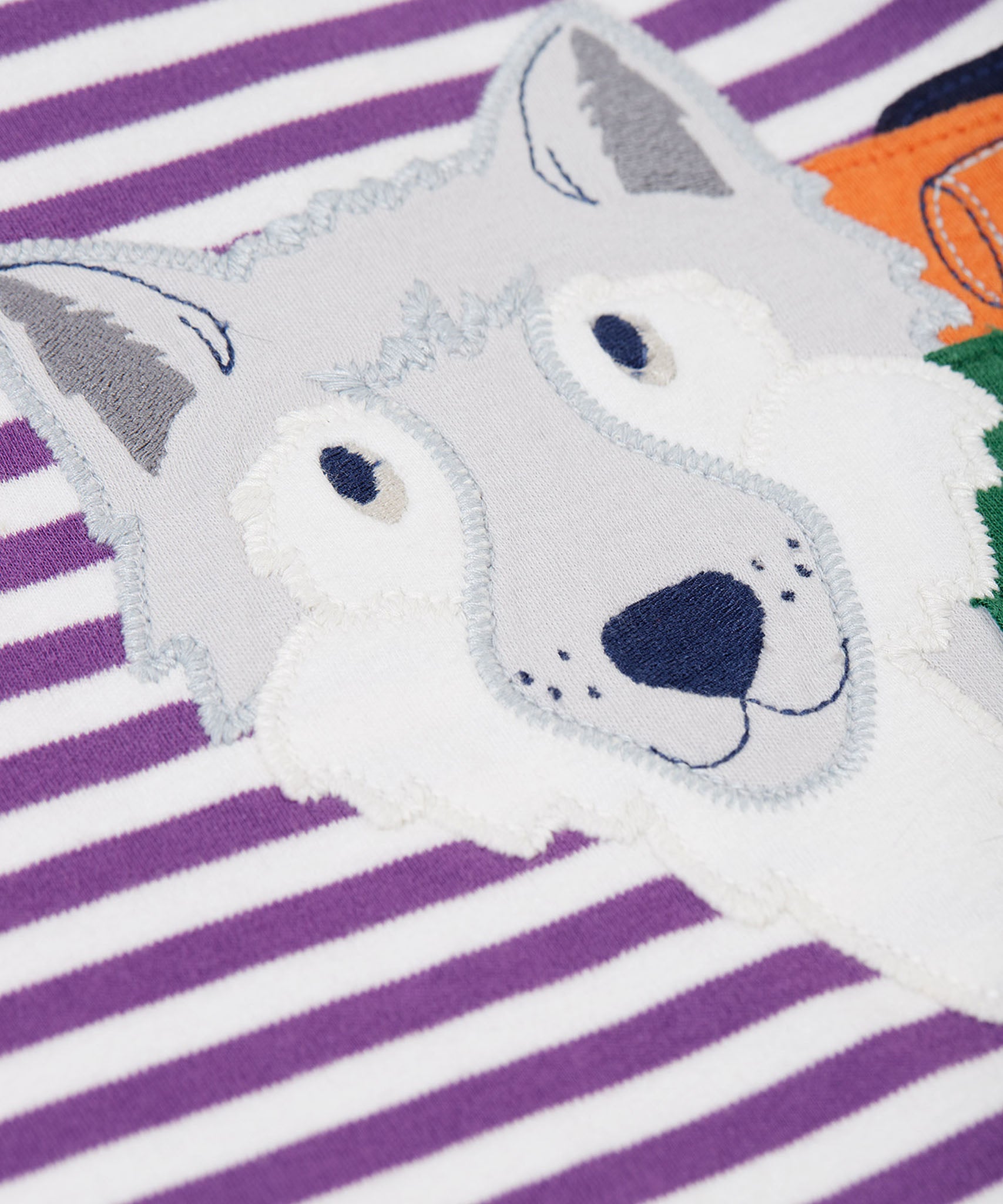 A close up of the wolf's face on the front of the Frugi Otis circular organic cotton violet purple long sleeved stripe top with wolf applique.