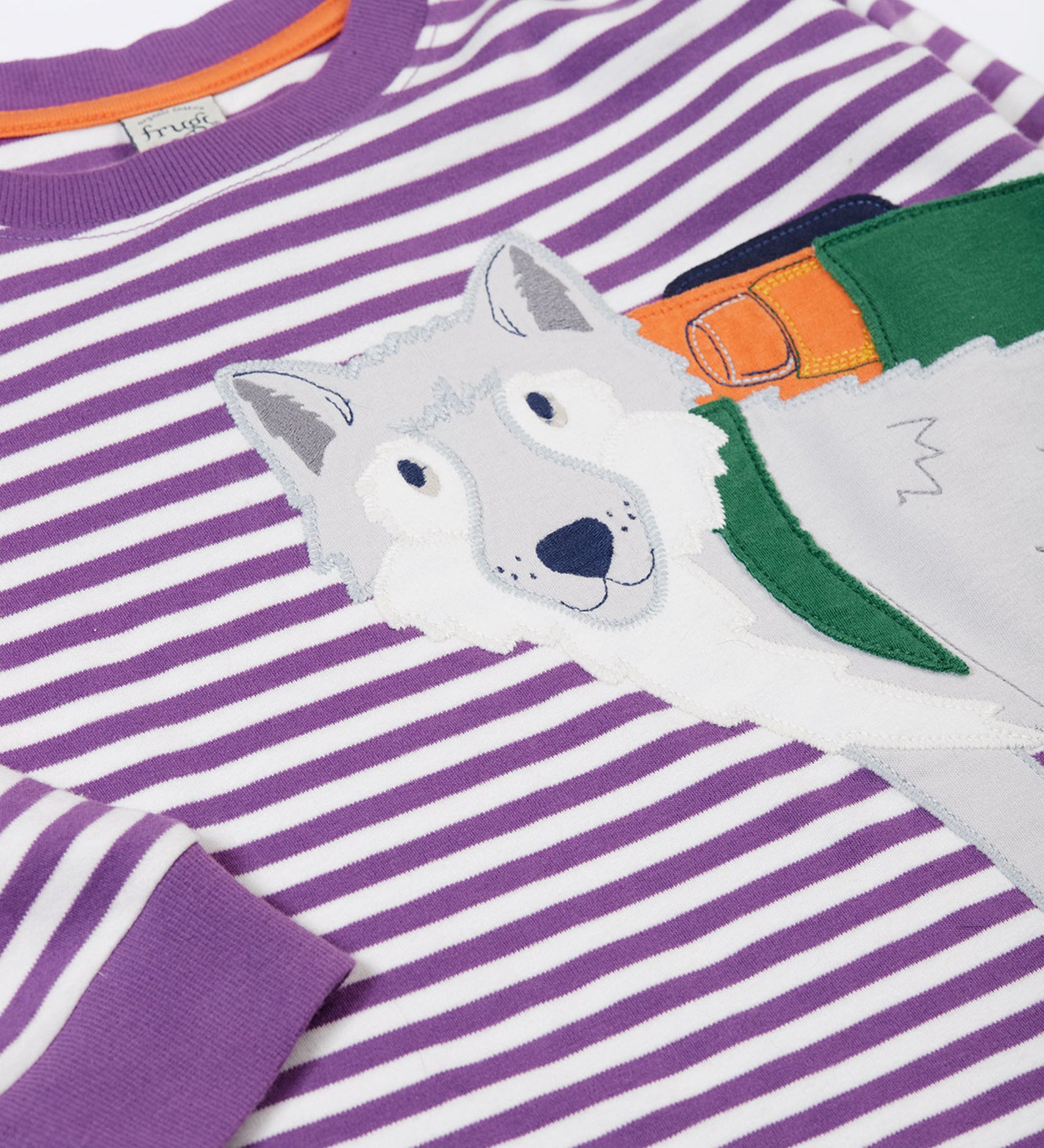 A close up of the wolf applique on the front of the Frugi Otis circular organic cotton violet purple long sleeved stripe top.