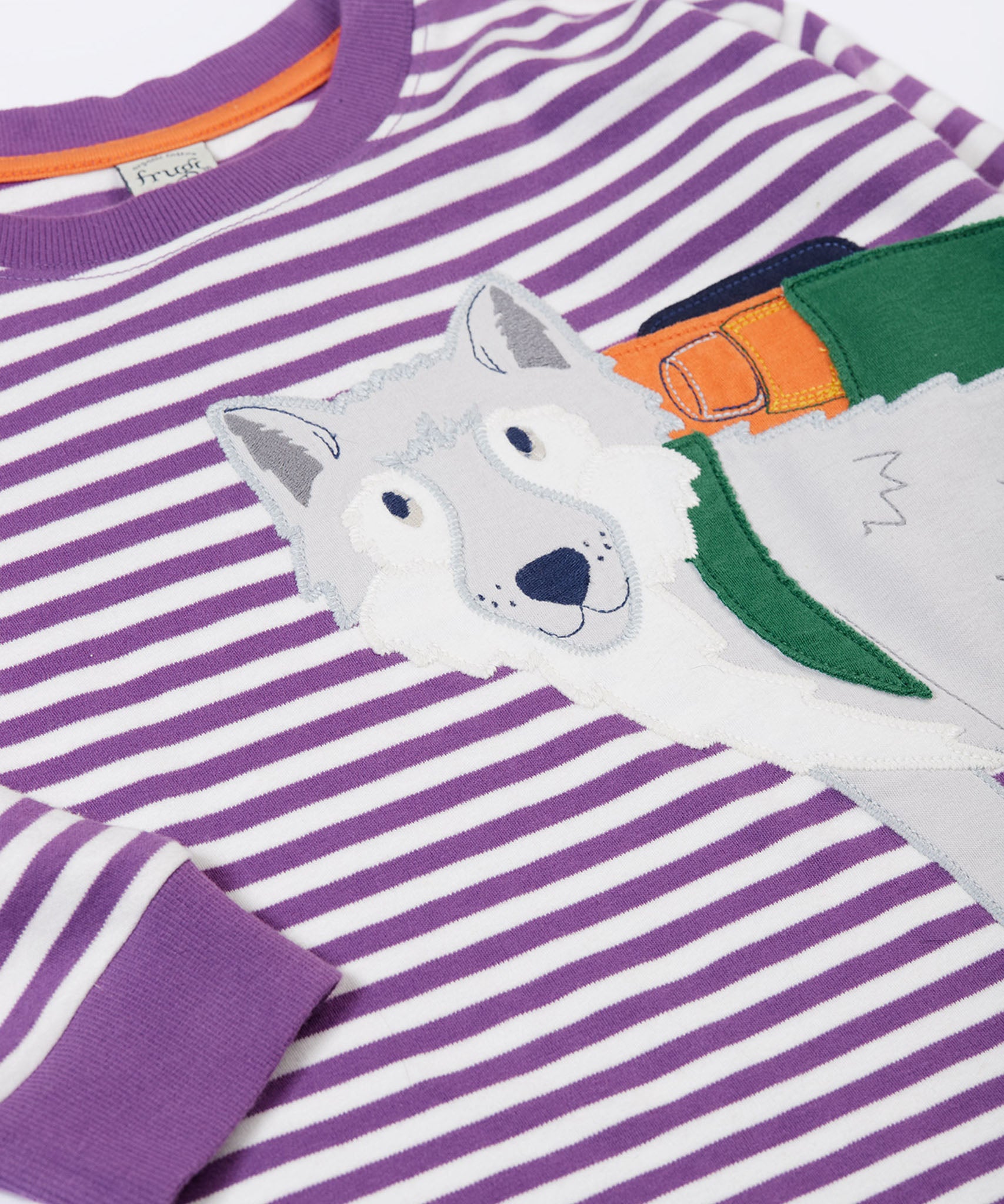 A close up of the wolf applique on the front of the Frugi Otis circular organic cotton violet purple long sleeved stripe top.