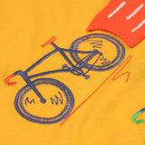 A super close up of the orange coloured embroidered bike on teh front of the Frugi Owen long sleeved child's top. 