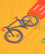 A super close up of the orange coloured embroidered bike on teh front of the Frugi Owen long sleeved child's top. 