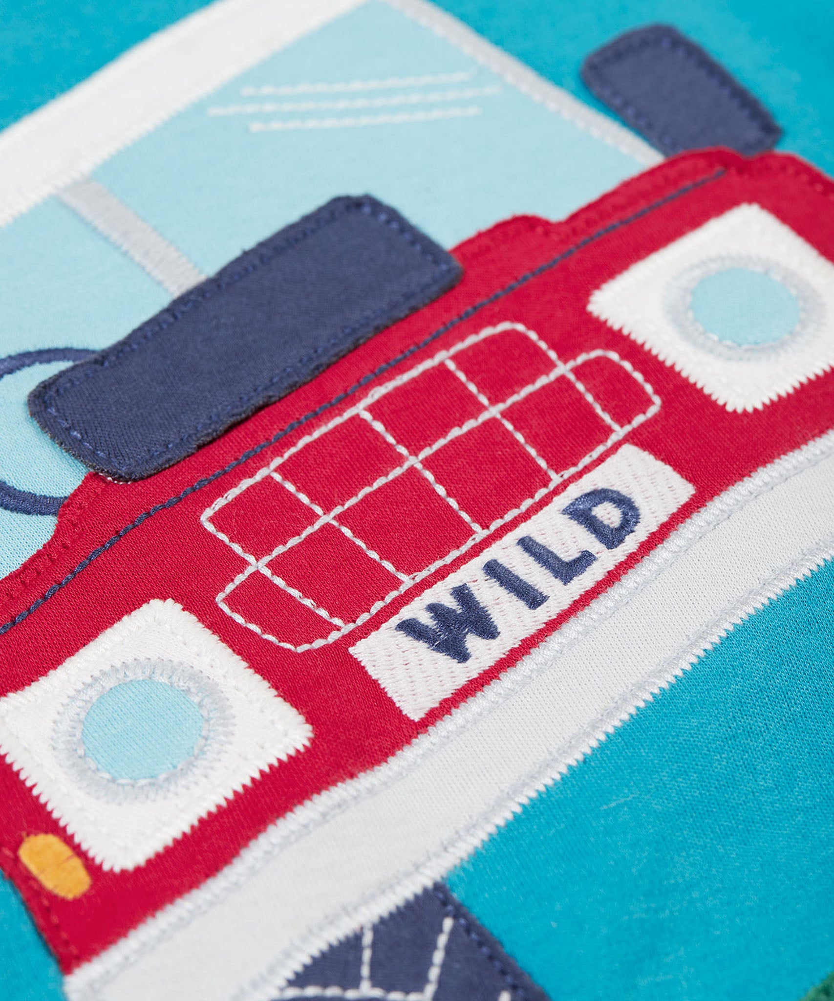 A super close up view of the truck on the front of the Frugi Organic Cotton Owen Panel Circular Top in a Boat Blue colour with Truck design.