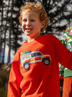 Child wearing the Frugi owen organic cotton long sleeved orange with a mountain rescue vehicle on the front. 