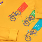 A close up of the embroidered and applique details on the front of the Frugi Owen top.  Three embroidered bicycles each with different coloured applique roads behind them.