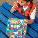 Child eating an apple, holding a Frugi fun frenzy pack a lunch bag. A multicoloured abstract cloud design. Main and a small front compartment and a carry handle.