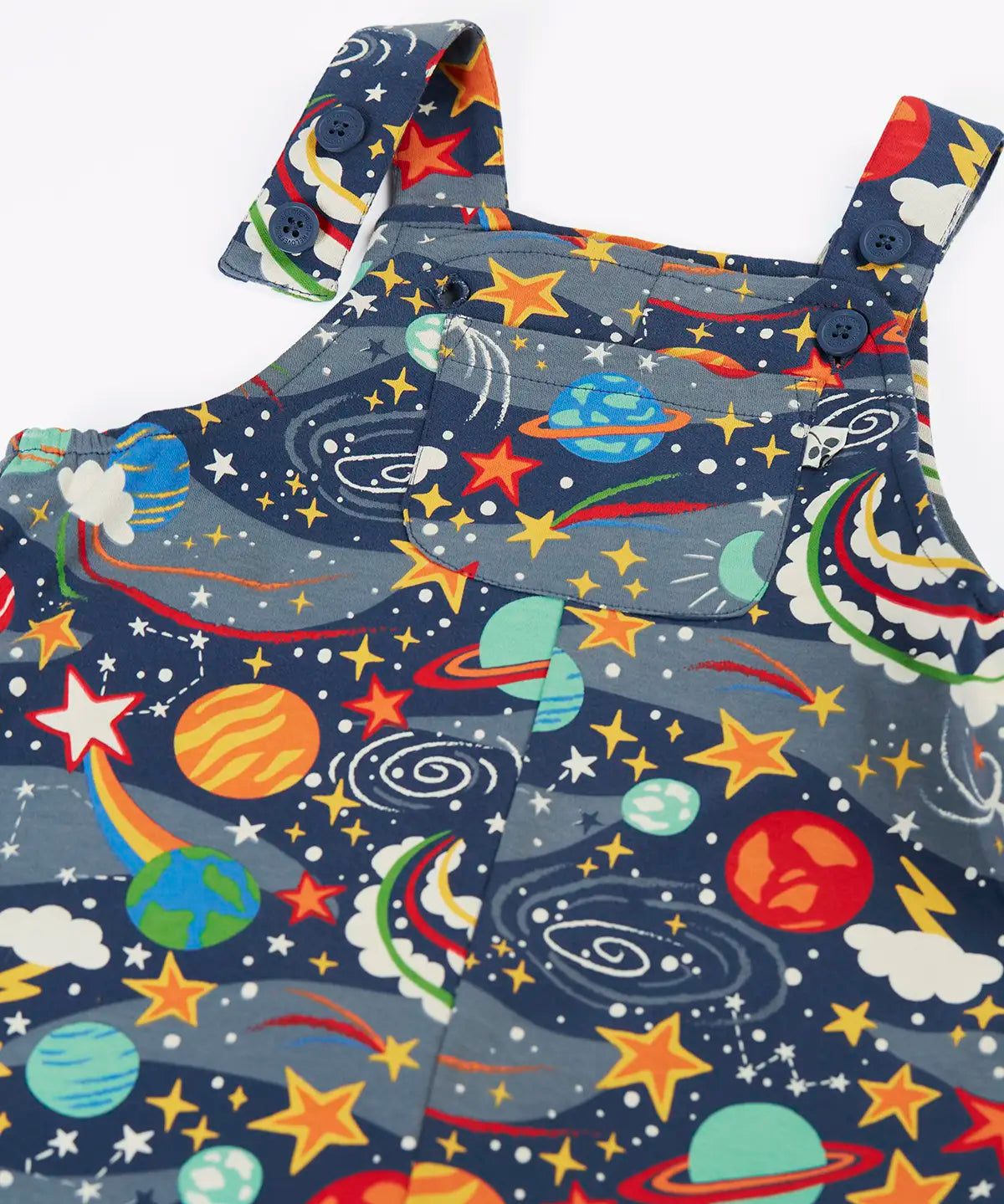 Close up of the button up straps and chest pocket on the front of the Frugi parsnip organic cotton dungaree in navy with an all over explore the stars print.