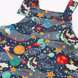 Close up of the button up straps and chest pocket on the front of the Frugi parsnip organic cotton dungaree in navy with an all over explore the stars print.
