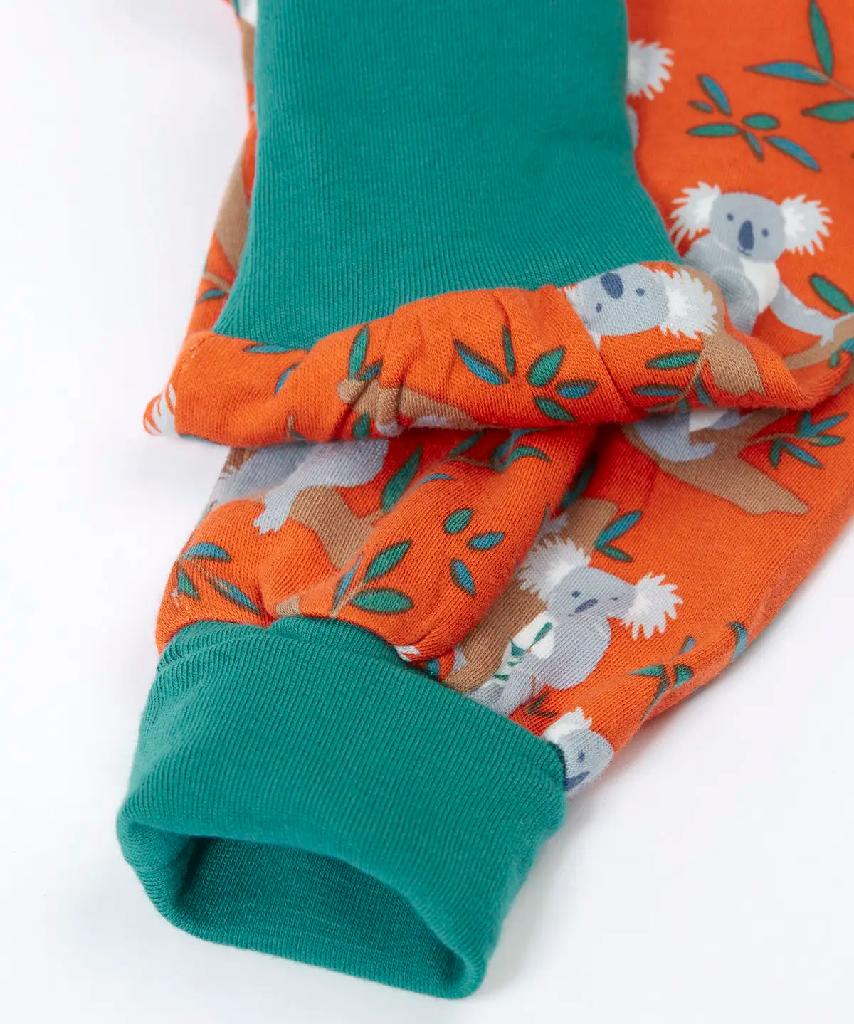 Frugi GOTS organic cotton parsnip pants in orange with a repeating koala print showing a close up of the teal fold up cuffs for extender wear