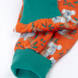 Frugi GOTS organic cotton parsnip pants in orange with a repeating koala print showing a close up of the teal fold up cuffs for extender wear