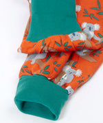 Frugi GOTS organic cotton parsnip pants in orange with a repeating koala print showing a close up of the teal fold up cuffs for extender wear