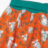 Frugi GOTS organic cotton parsnip pants in orange with a repeating koala  print and a teal elasticated waistband for extender wear