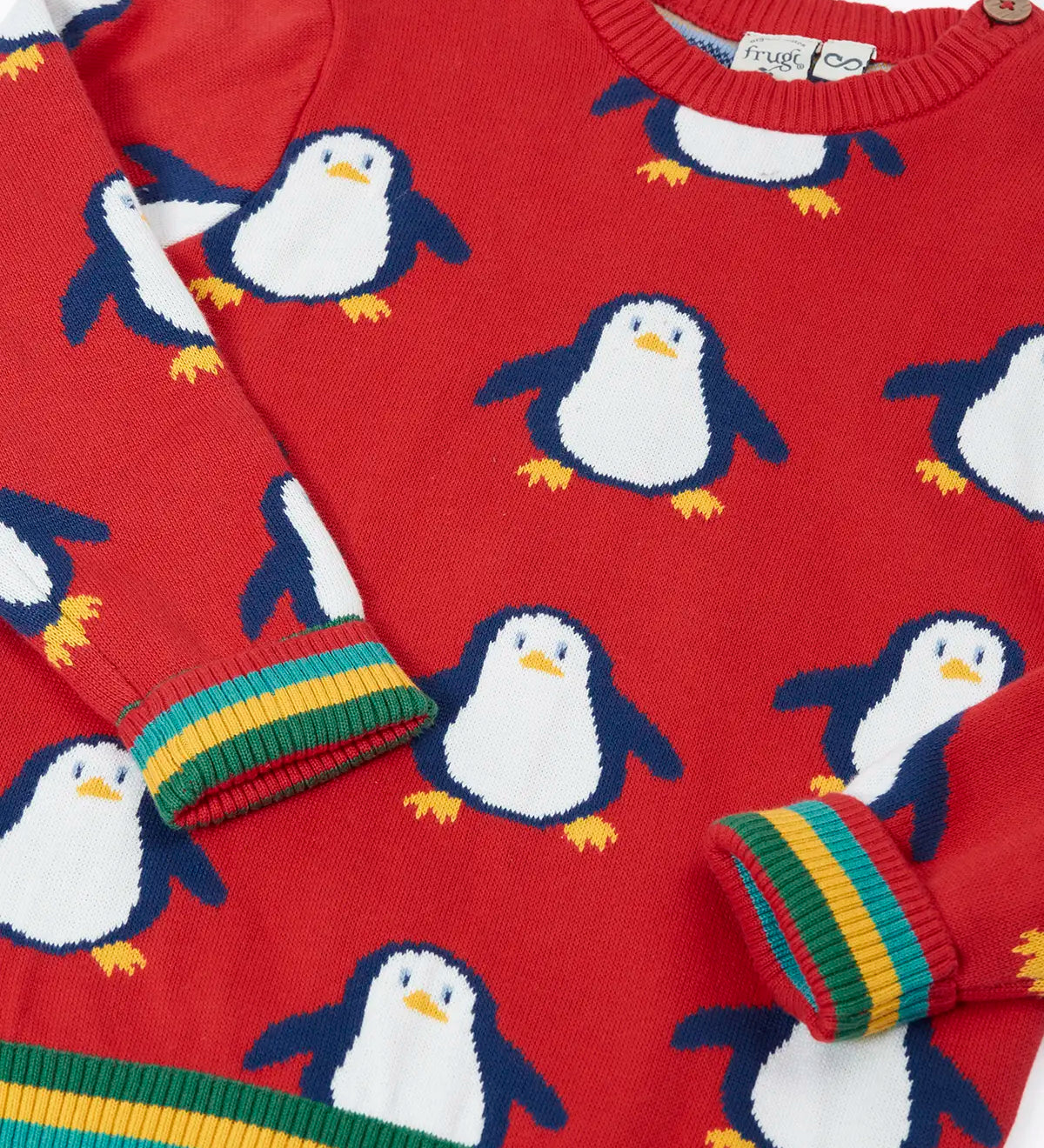 Close up of the Frugi scarlet penguins organic cotton jolly knitted jumper showing the rainbow stripe hemline and arm cuffs.