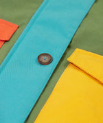 A close up of the Frugi khaki penhale colourblock parka showing the button fastener and pocket detail on organic cotton fabric