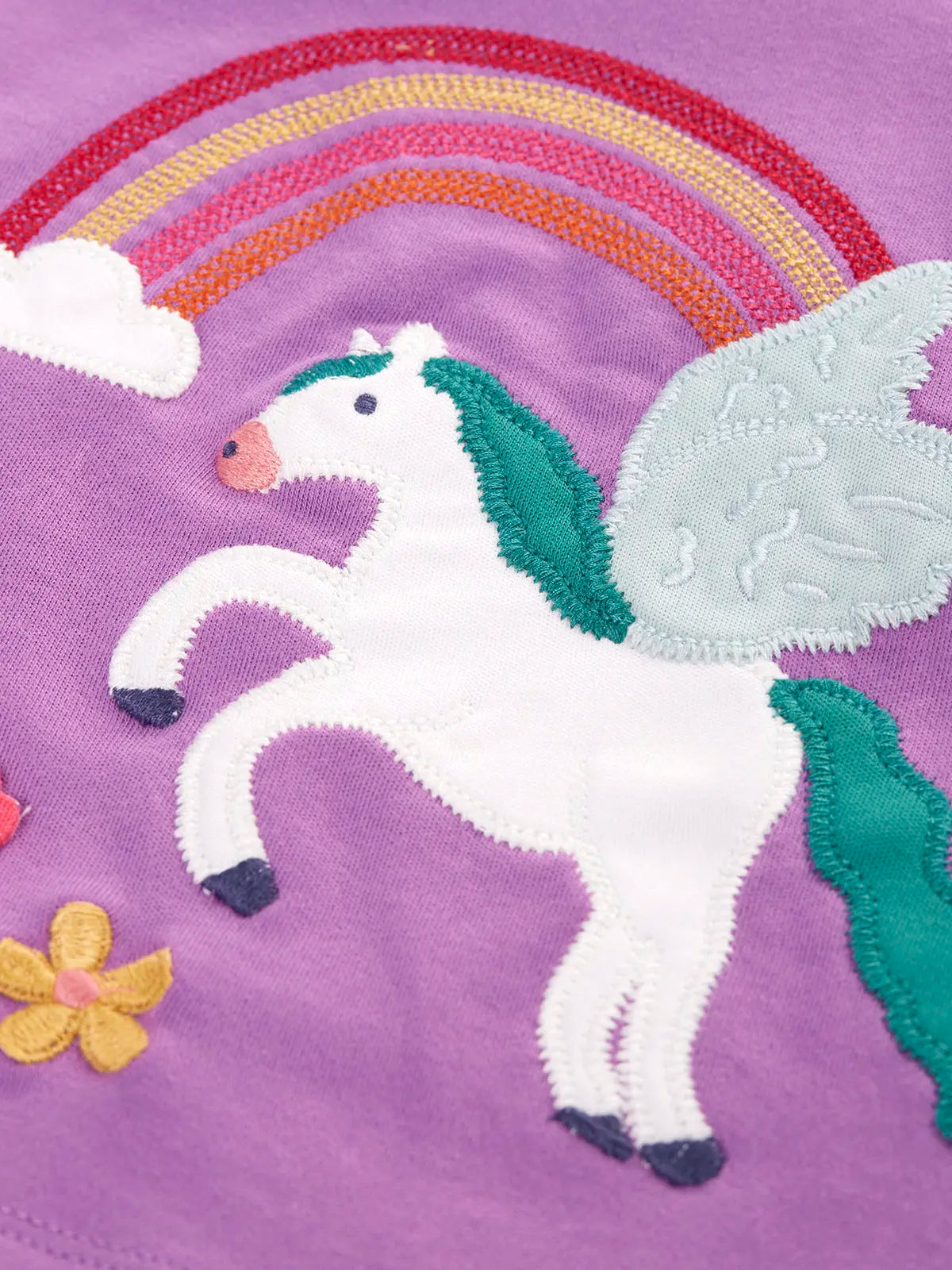 Close up of the white pegasus applique with rainbow and flowers details on the Frugi organic cotton periwinkle purple caris pegasus child's top. 