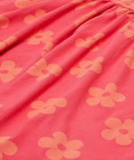 A close up of the Frugi kids summer flamingo / flower dress. Showing the detail of the coral flowers print on pink organic cotton fabric
