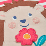 A close up of the hedgehog applique on the front of the Frugi Easy On pink breton stripe hedgehog applique short sleeved organic cotton T-Shirt. The hedgehog is holding a pink flower and there is a little bee flying above.