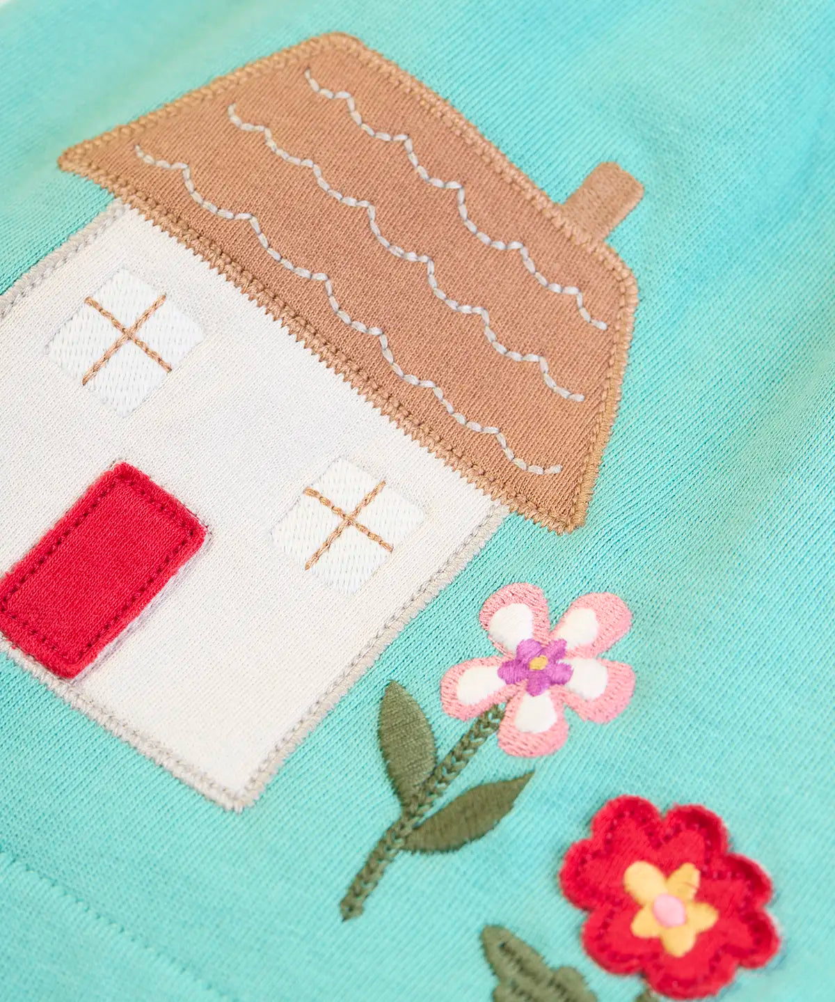 Frugi GOTS 100% organic cotton pinafore dress outfit showing a close up of the Highland cottage applique on the hem