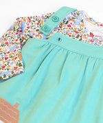 Frugi GOTS 100% organic cotton pinafore dress outfit showing the adjustable shoulder straps and a floral top underneath