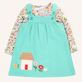 Frugi Pippa light moss green pinafore dress outfit with highland fields print long sleeved body. The light green dress has a highland house and floral applique detail on the front