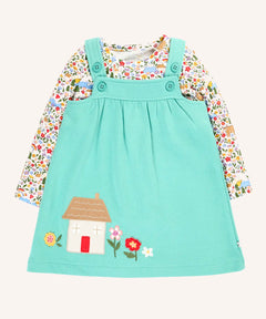 Frugi Pippa light moss green pinafore dress outfit with highland fields print long sleeved body. The light green dress has a highland house and floral applique detail on the front