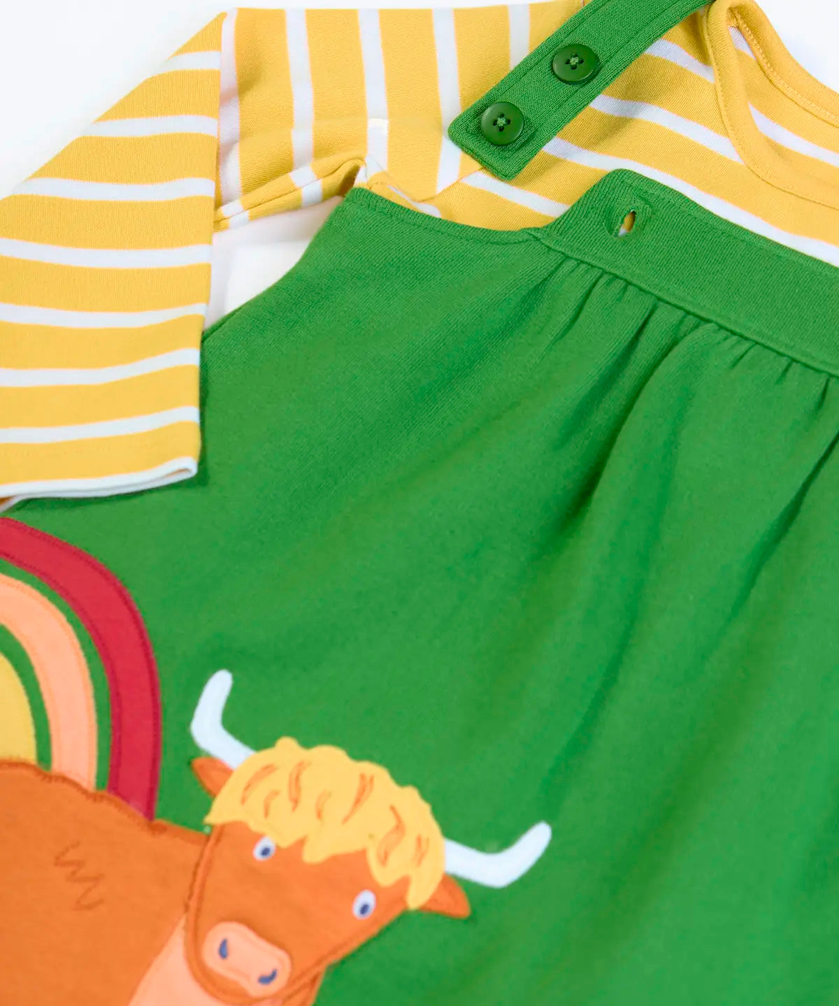 Frugi GOTS 100% organic cotton green pinafore dress outfit showing the adjustable shoulder straps and a yellow and white striped top underneath