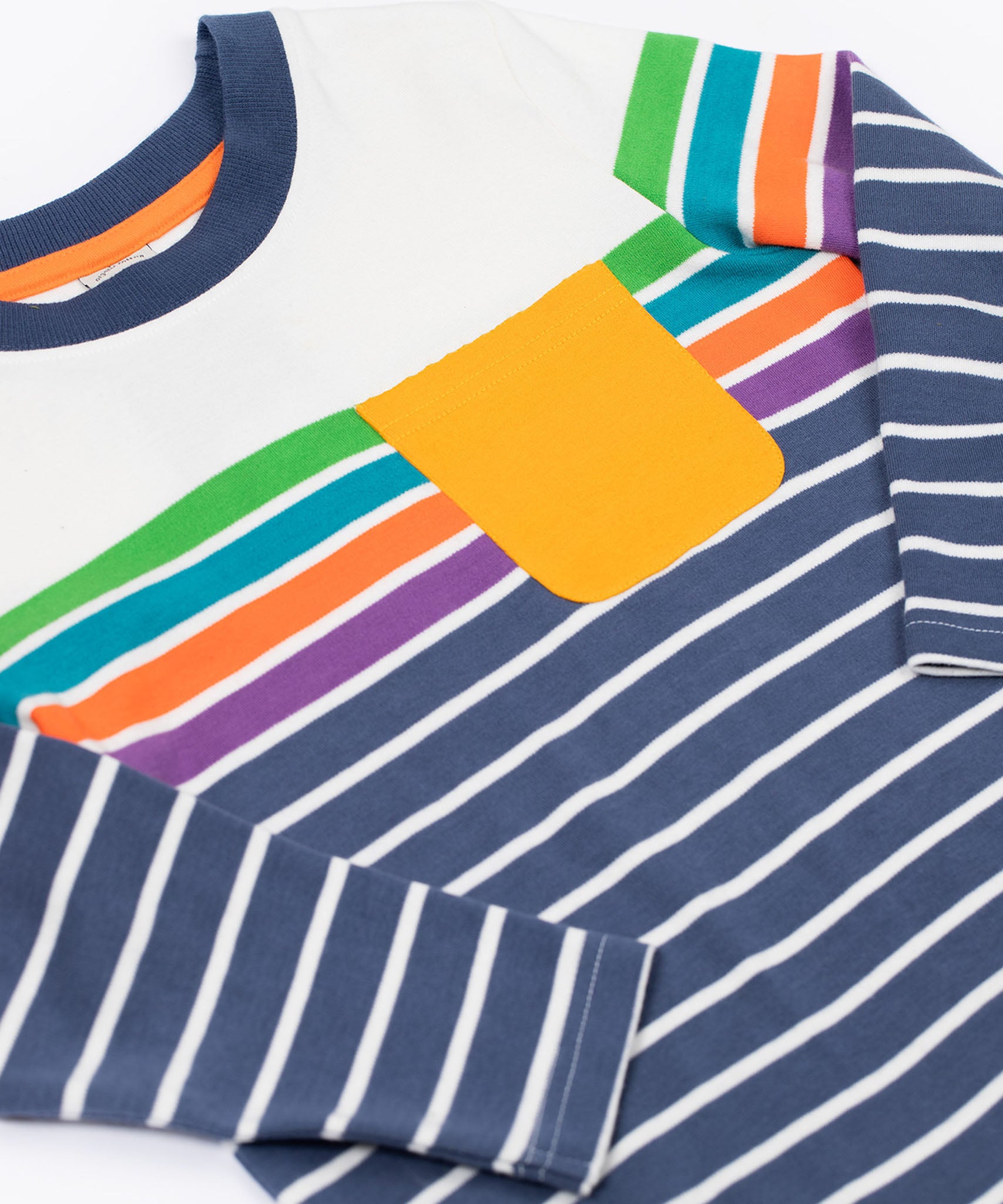 A close up of the Frugi Piran pocket navy striped organic cotton child's long sleeved top. The top has a navy and white stripes at the bottom, then 4 coloured stripes and a white band at the top with a small yellow gold coloured pocket on the chest