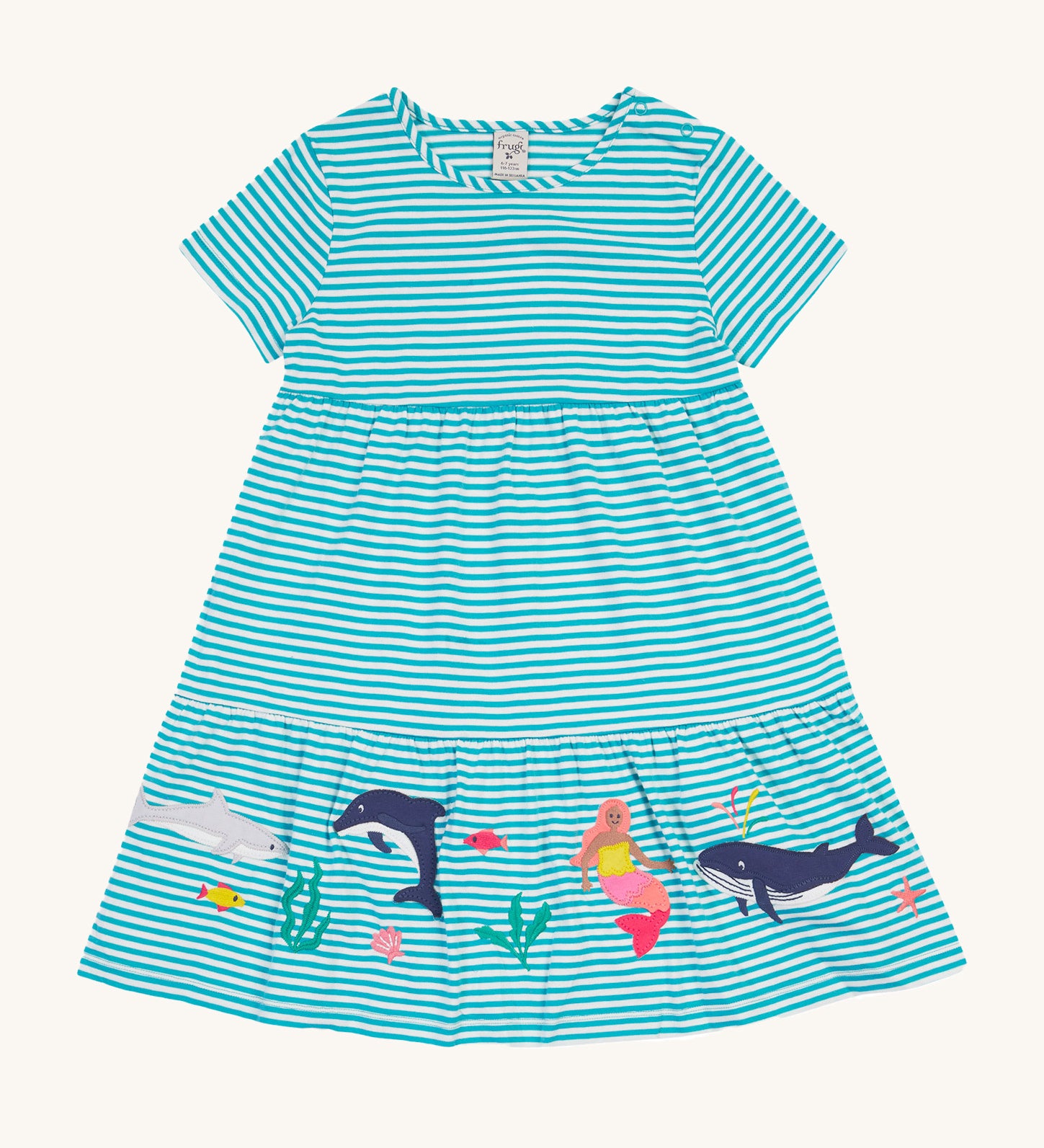 Frugi Pixy Sea Moss Mini Stripe Dress laid flat, with a Sealife print along the bottom, featuring whales, dolphins, sharks, a Mermaid and some small fish, surrounded by colorful seaweed.