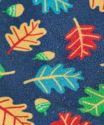 Frugi children's playtime waterproof coat with a multi-coloured acorn tumble print on a navy background, close up of water droplets formed on the material.